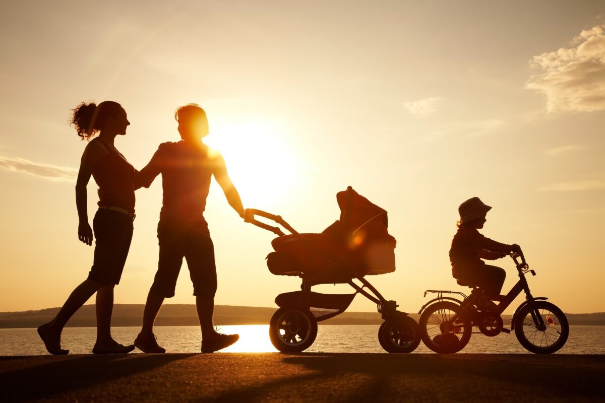 a family of four walking across the beach at sunset