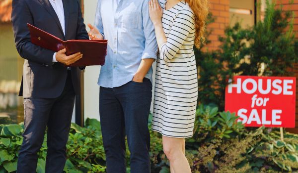 a young couple with a real estate agent buying a house