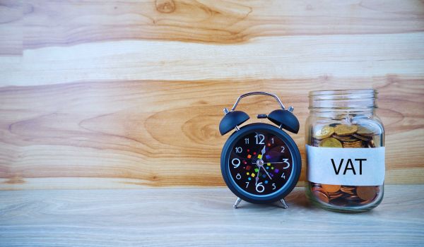 a clock next to a jar of coins that says VAT