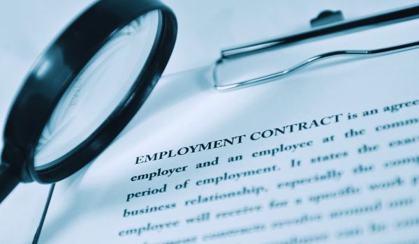 magnifying glass examining an employment contract