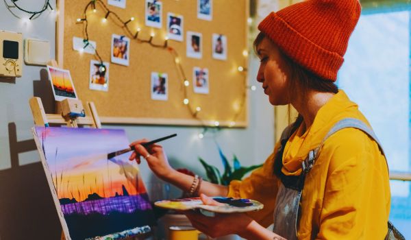 a woman paints a landscape picture in her studio