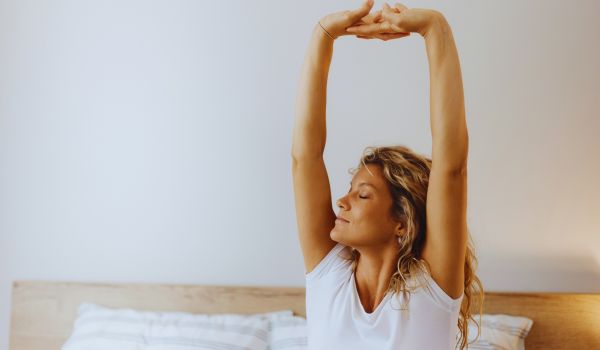 a woman stretches after waking up from sleep