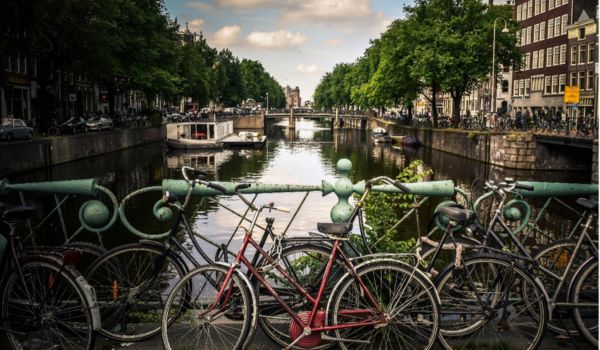 a bike leaning against an amsterdam canal on a grey day