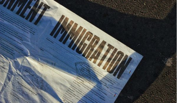 a newspaper on the ground with the word Immigration as a headline