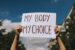 a woman holding a my body my choice sign