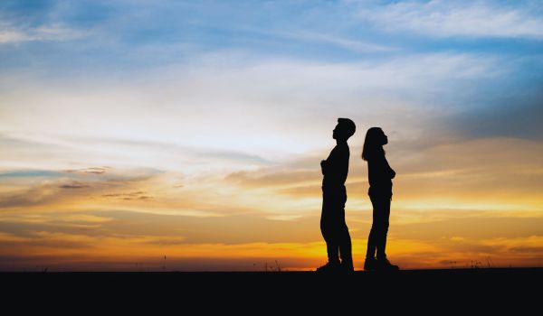 A quareling couple standing on a mountain turned against each other