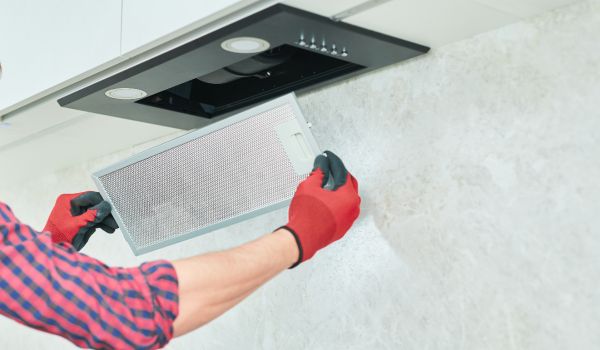 a man installs an extractor hood over his gas oven