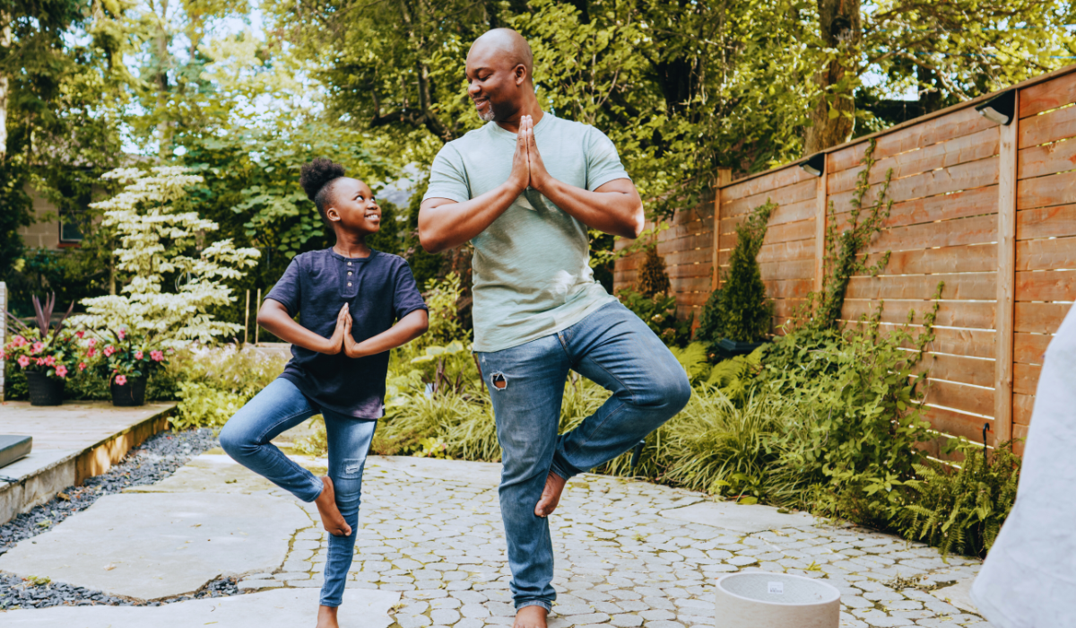 a father and daughter doing yoga outdoors