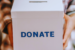 a person holding a donation box