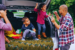 a family of four standing behind their car