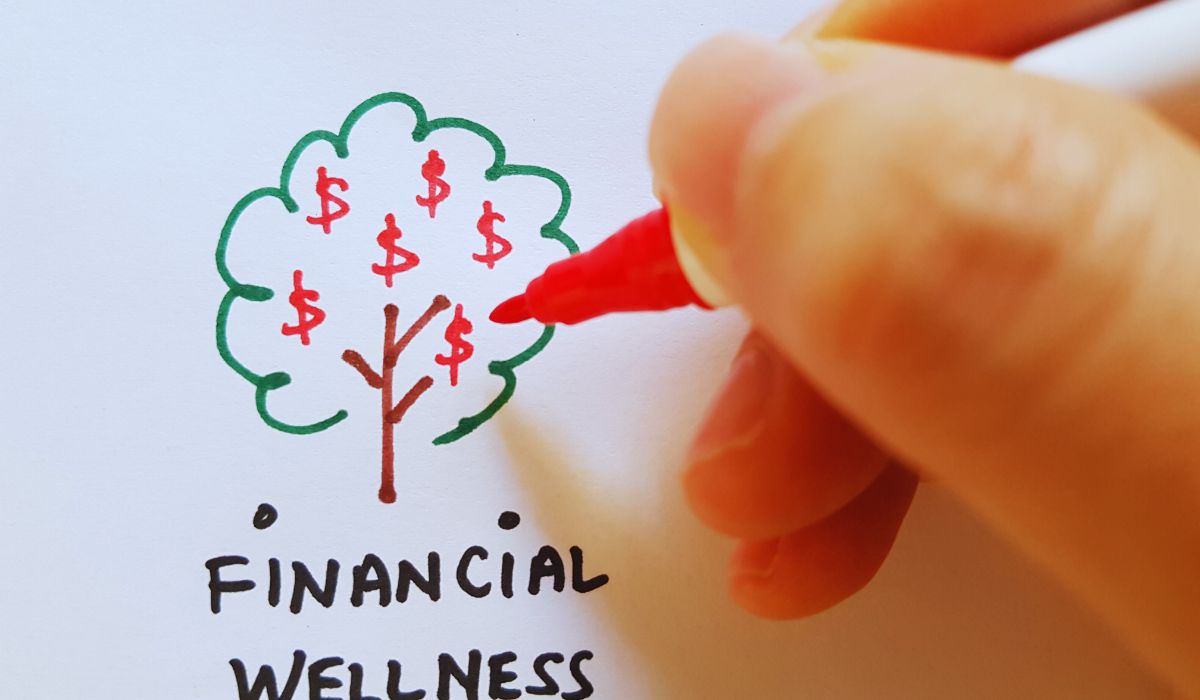 a hand draws a tree representing financial wellness plan